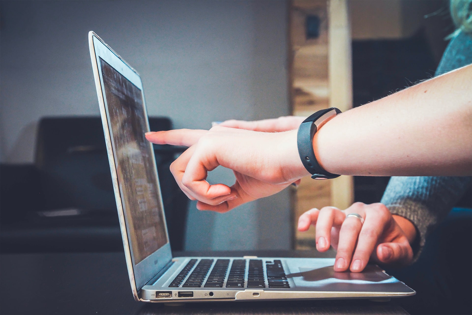Hands pointing at laptop screen for collaboration