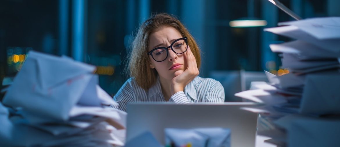 Tired woman working late at cluttered desk