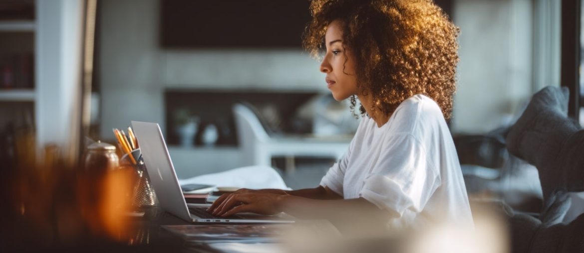 Woman working on laptop at home desk.