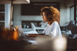 Woman working on laptop at home desk.