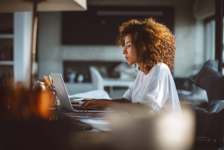 Woman working on laptop at home desk.