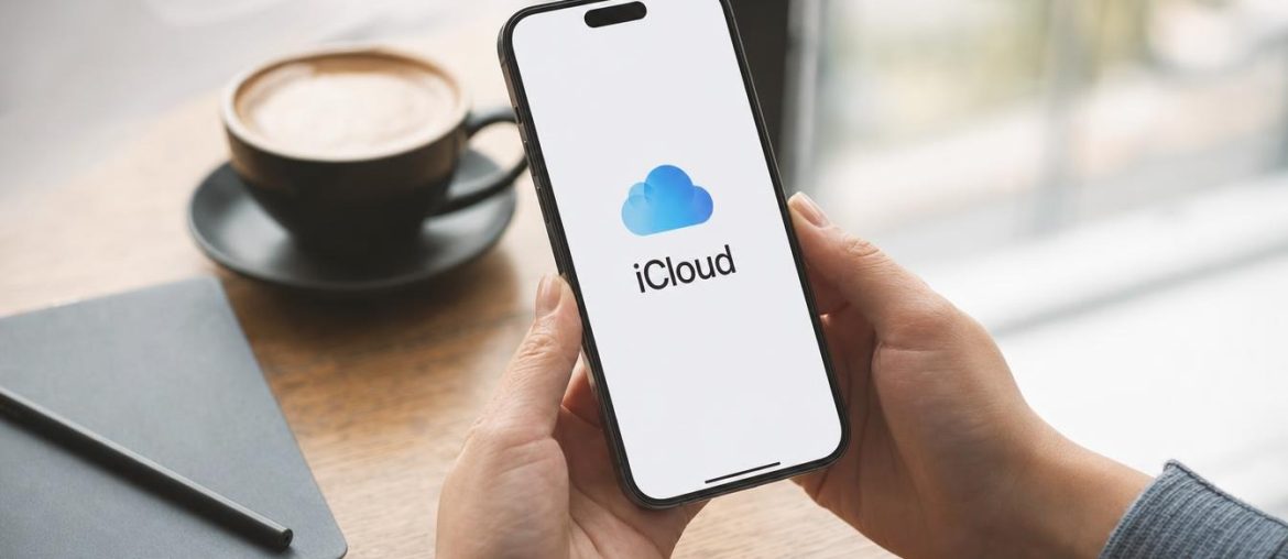 Hands holding an iPhone displaying the iCloud logo