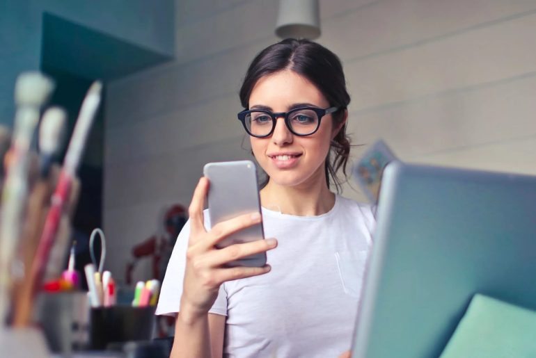 Mujer con gafas usando smartphone en oficina