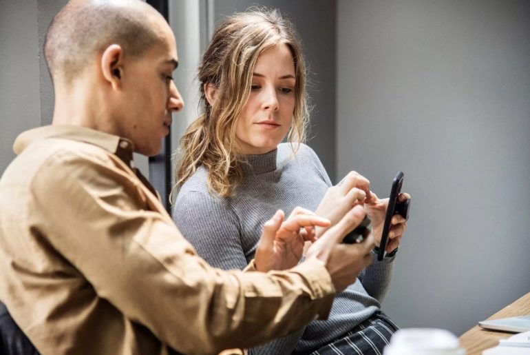 Personas colaborando con móvil en oficina moderna