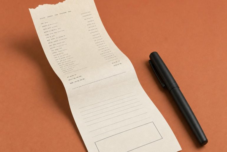 Ticket de caisse dont le bas se prolonge en formulaire à signer, avec une case de signature restée vide et un stylo encore capuchonné posé à côté
