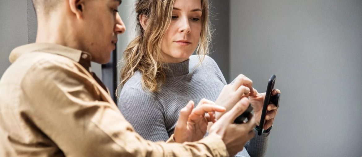 Due persone controllano insieme uno smartphone.