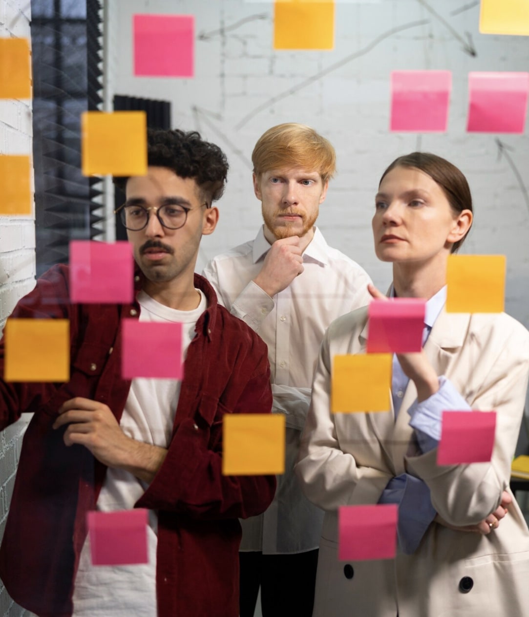 Persone che esaminano post-it colorati su vetro
