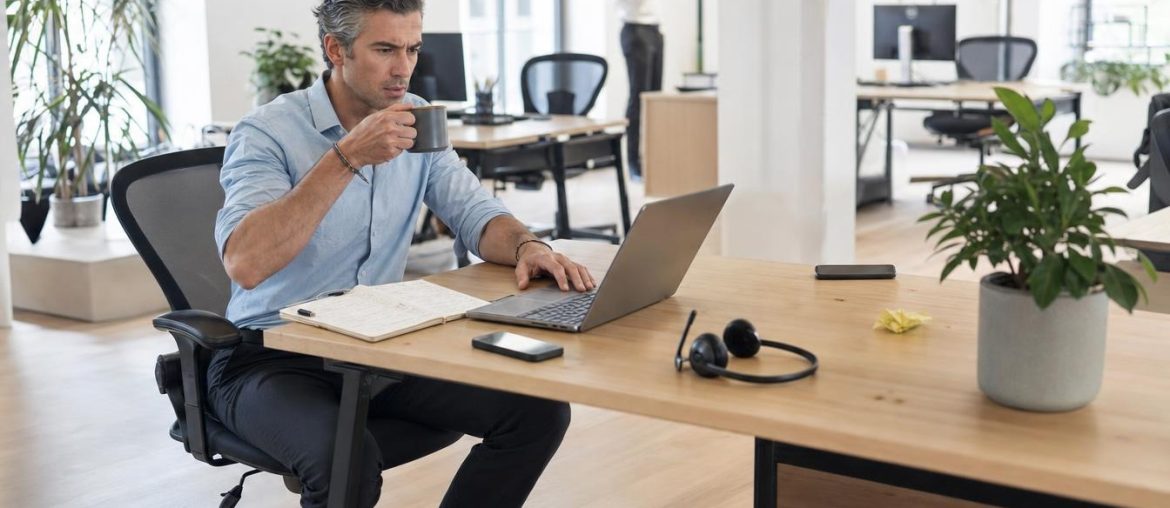 Firma email Outlook e Gmail: come crearla senza compromettere la consegna Uomo che lavora su un computer portatile in un ufficio luminoso
