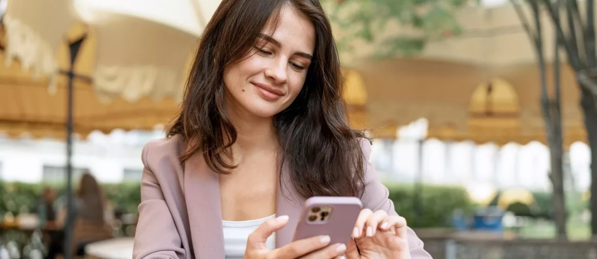 O surto do SMS conversacional: uma revolução na comunicação digital Mulher utilizando um smartphone ao ar livre.